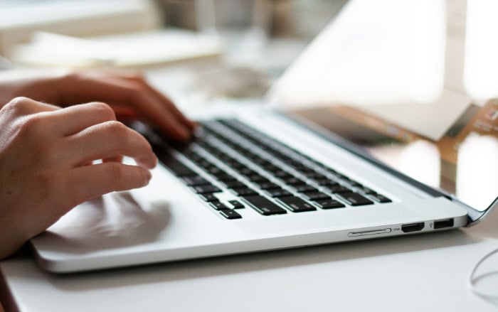 Close up view of hands typing on laptop keyboard