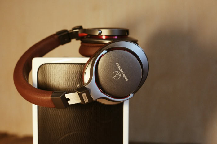 Closed back headphones with brown cushions on a speaker