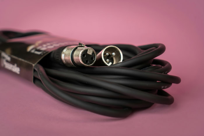 Coiled XLR microphone cable on a pink background