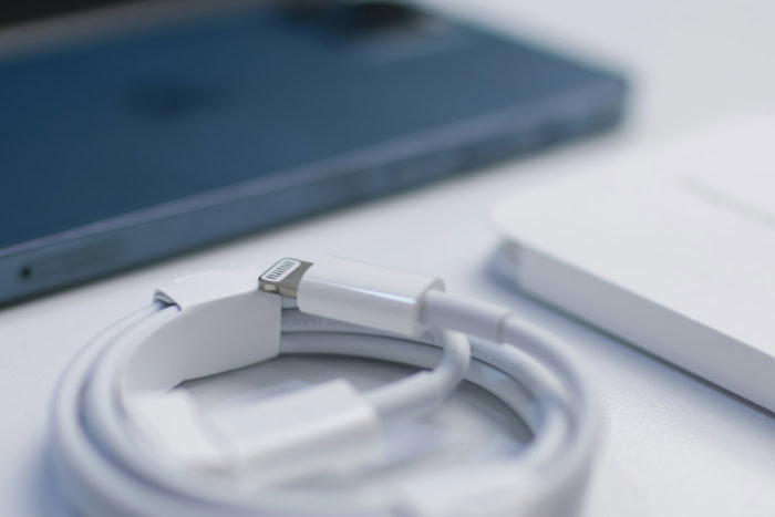 Coiled white Apple Lightning cable next to blue iPhone