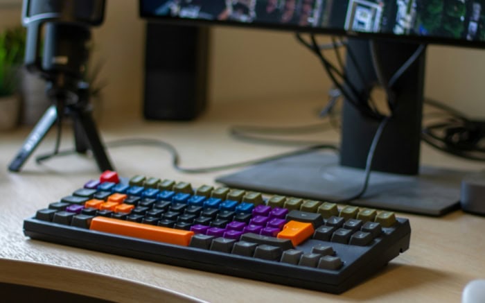 Colorful wired mechanical keyboard on a gamers desk with monitor
