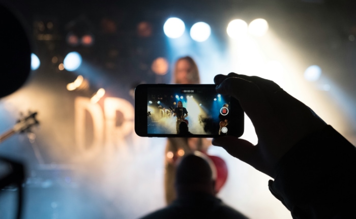 Concert goer recording a live performance on a smartphone