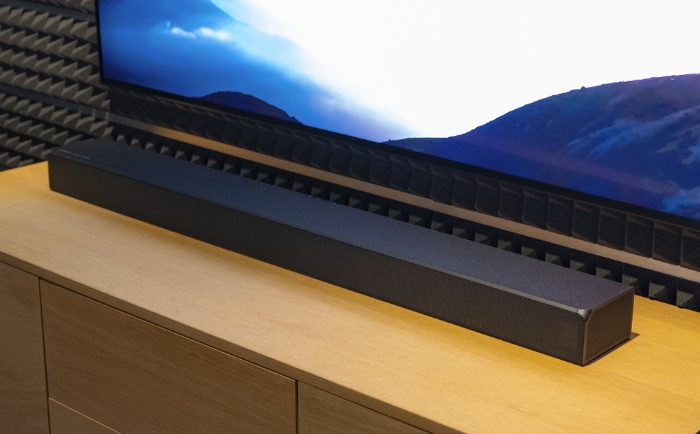 Contemporary soundbar on wooden cabinet below wall mounted TV