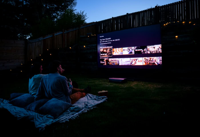 Couple watching movie on outdoor projector screen at night