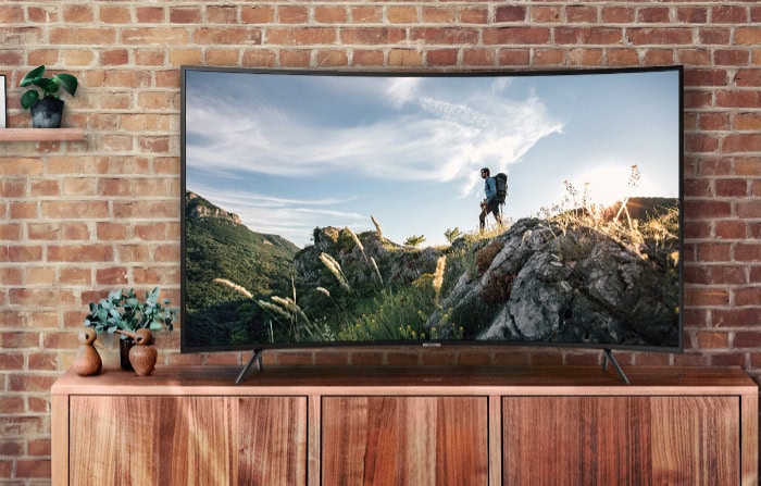 Curved TV with nature scenery against brick wall