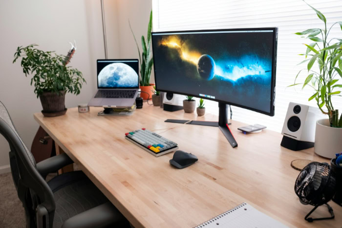 Curved monitor desk setup with plants and laptop