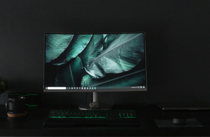 Dark minimalist PC setup with green lit keyboard and plant