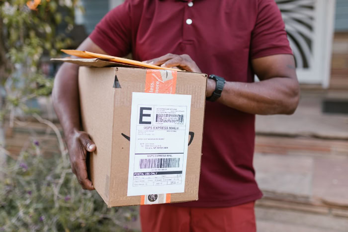 Delivery worker holding Amazon package box and envelopes resized