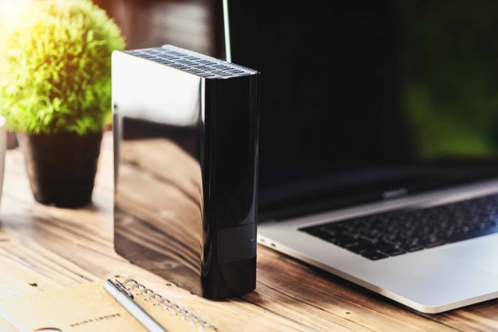 Desktop external hard drive next to a laptop on a desk