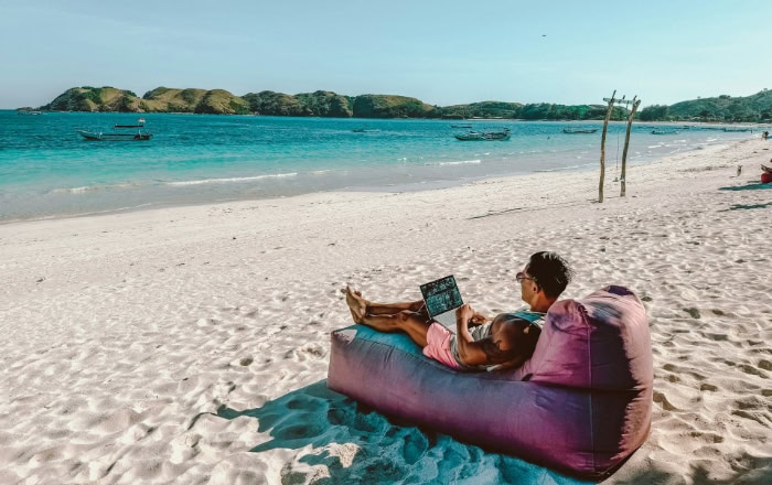 Digital nomad working on laptop on tropical beach