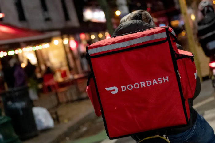DoorDash delivery person with red backpack at night
