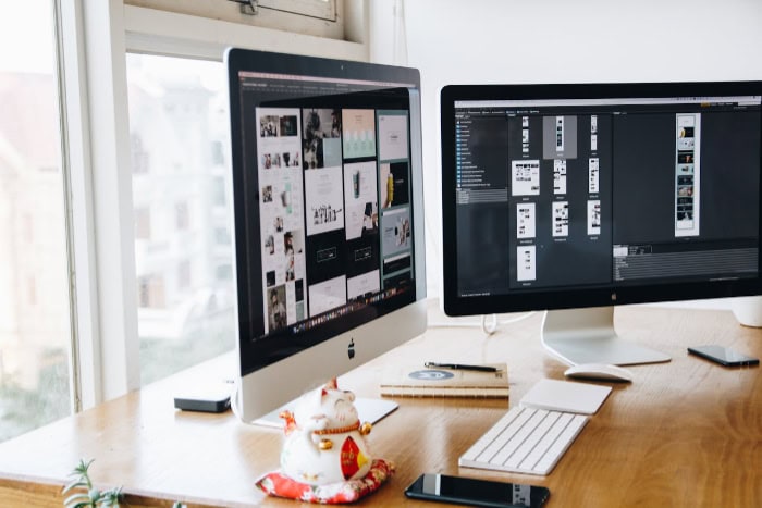 Dual iMac workstation displaying graphic design software