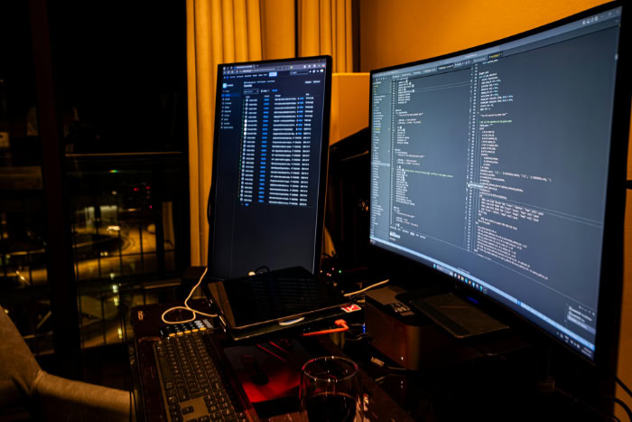 Dual monitors displaying code in dark room