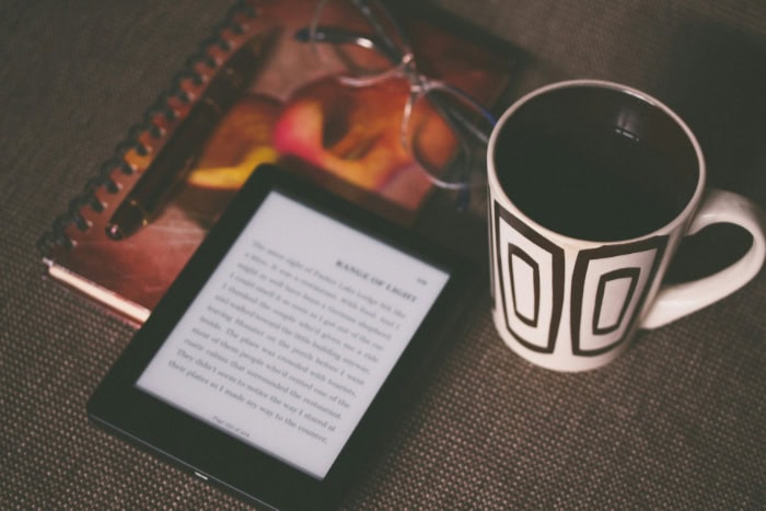 E reader next to a coffee cup and notebook