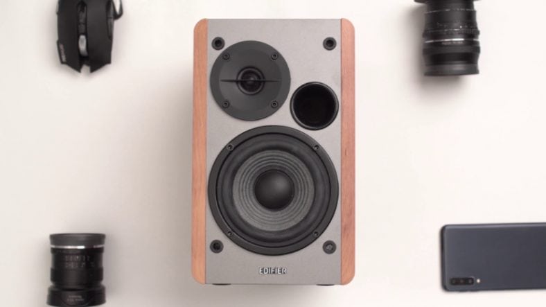 Edifier R1280T in between black gadgets on white surface