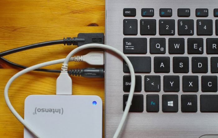 External hard drive connected to laptop keyboard via USB cables