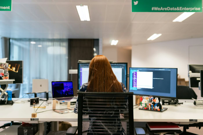 Female developer working at a multi monitor office desk