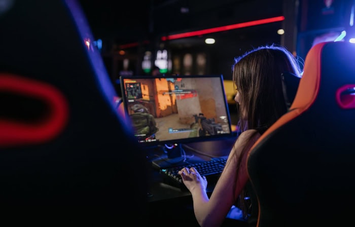 Female gamer playing first person shooter in esports setup