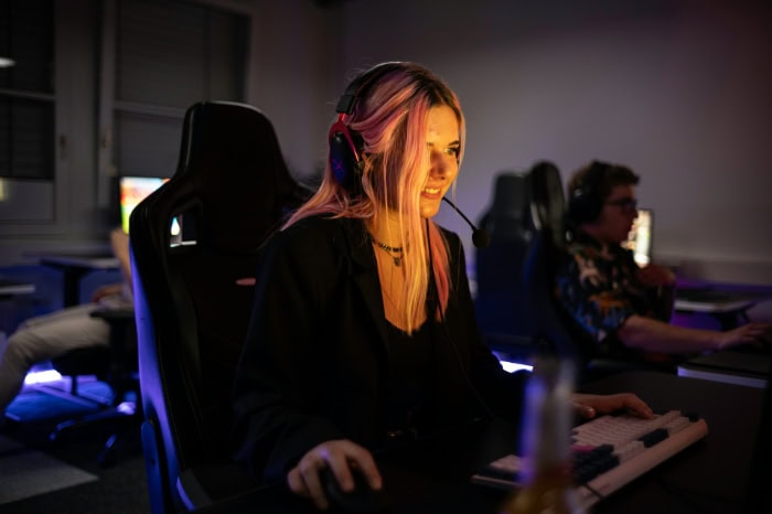 Female streamer with headset smiling at gaming setup