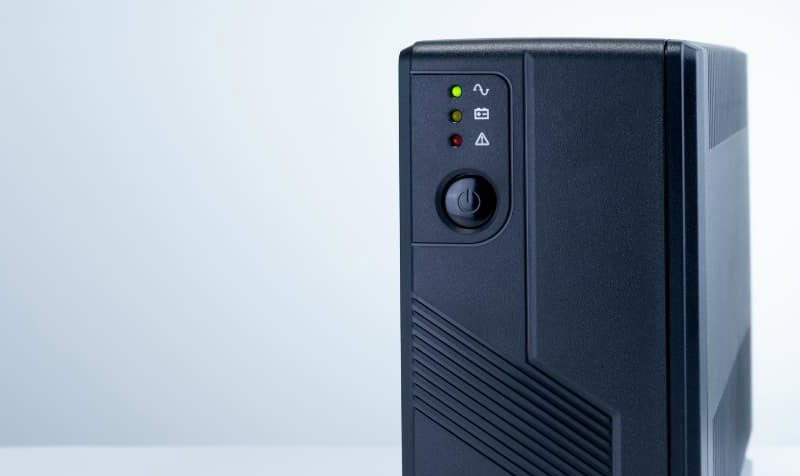 Front panel of a black UPS with indicator lights