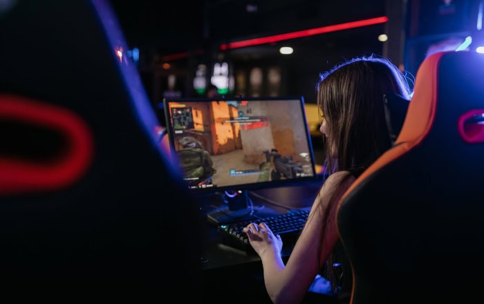 Gamer playing video game on computer in dim setup