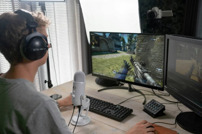 Gamer streaming first person shooter game with dual monitors