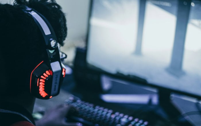 Gamer wearing headset with red LED lights playing on computer