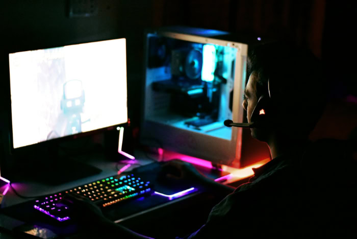 Gamer with headset playing PC in dark room