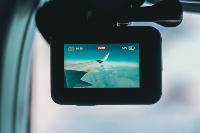 GoPro screen showing airplane wing above clouds