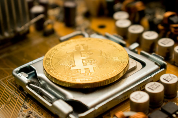 Gold Bitcoin coin placed on motherboard components
