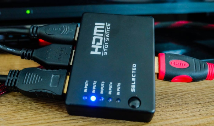 HDMI switch with multiple cables connected and blue indicator lights on