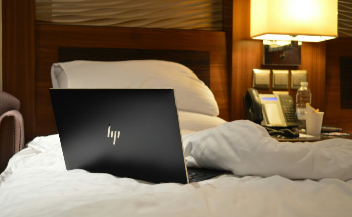 HP laptop on hotel bed with pillows