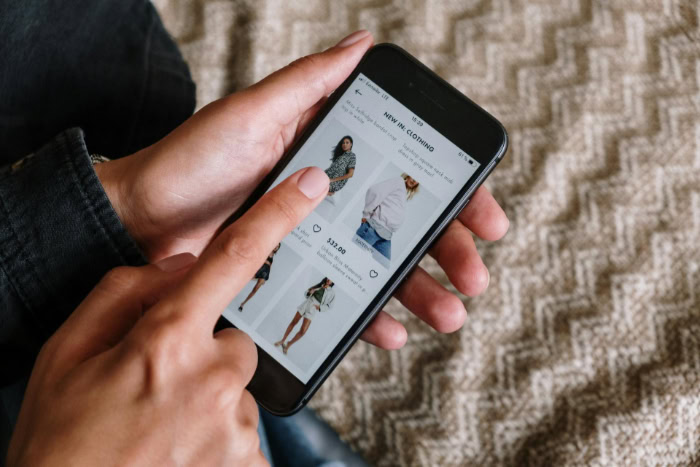 Hand browsing clothing items on a smartphone