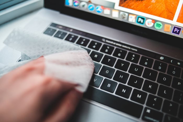 Hand cleaning a laptop keyboard with a cloth