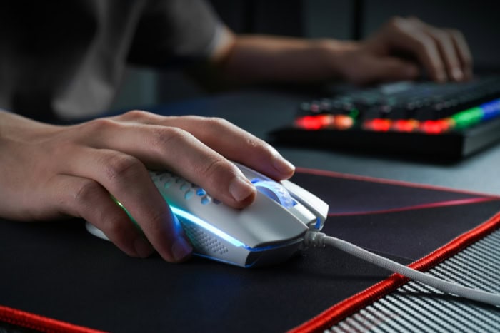 Hand gripping gaming mouse with RGB lighting on mousepad