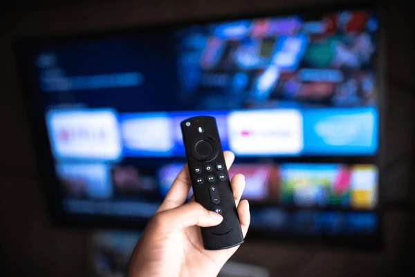 Hand holding Amazon Fire TV remote in front of television