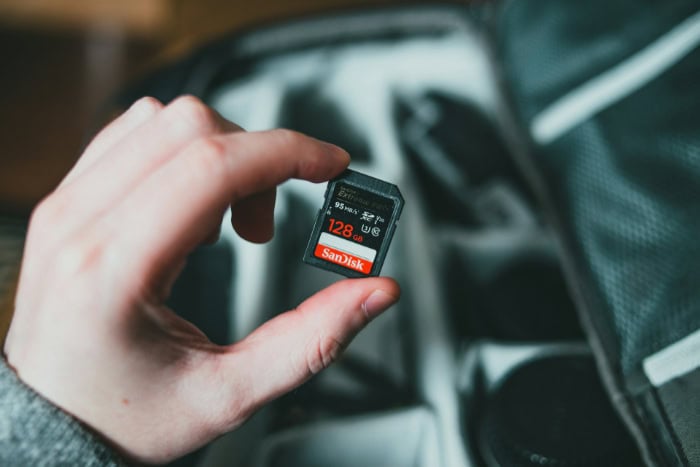 Hand holding a SanDisk 128GB SD card