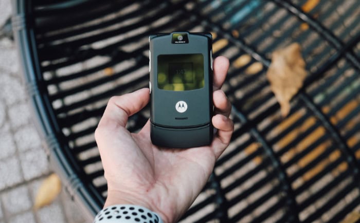 Hand holding a classic Motorola flip phone outdoors