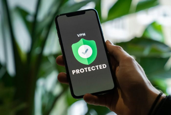 Hand holding a phone with VPN protection icon displayed