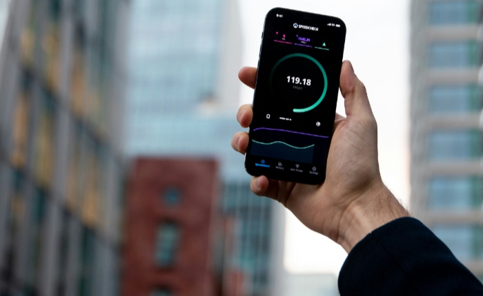 Hand holding a smartphone with a speed test app displaying fast internet speed