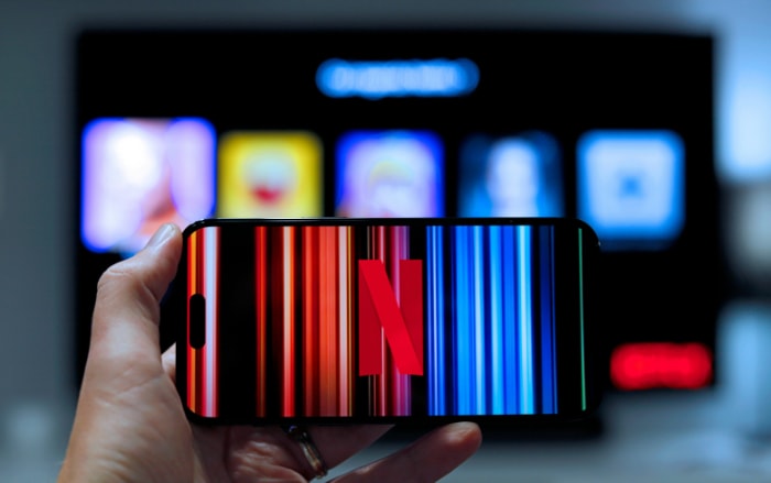 Hand holding a smartphone with the Netflix logo displayed