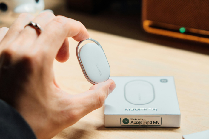 Hand holding a white Xiaomi Tag smart tracker