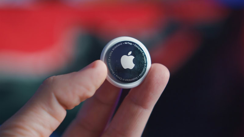 Hand holding an Apple AirTag tracking device
