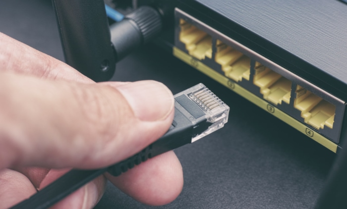Hand holding an Ethernet cable before connecting to a router