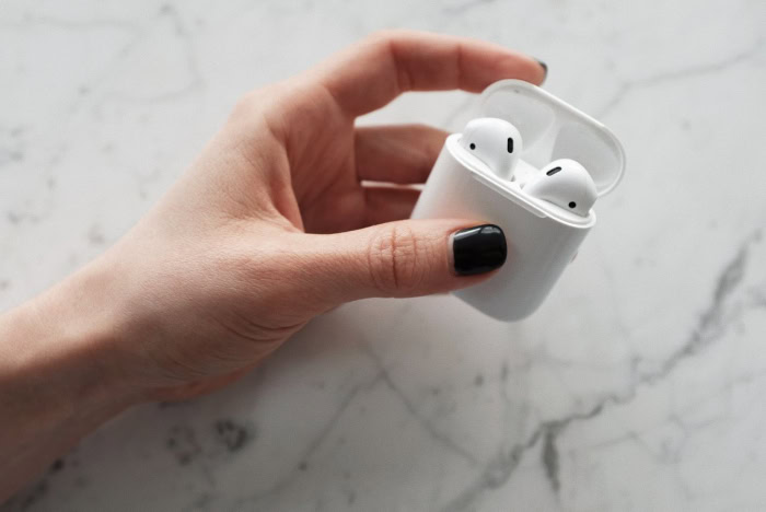 Hand holding an open AirPods case with earbuds