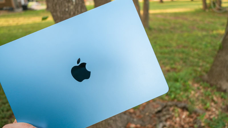 Hand holding blue MacBook Air lid outdoors