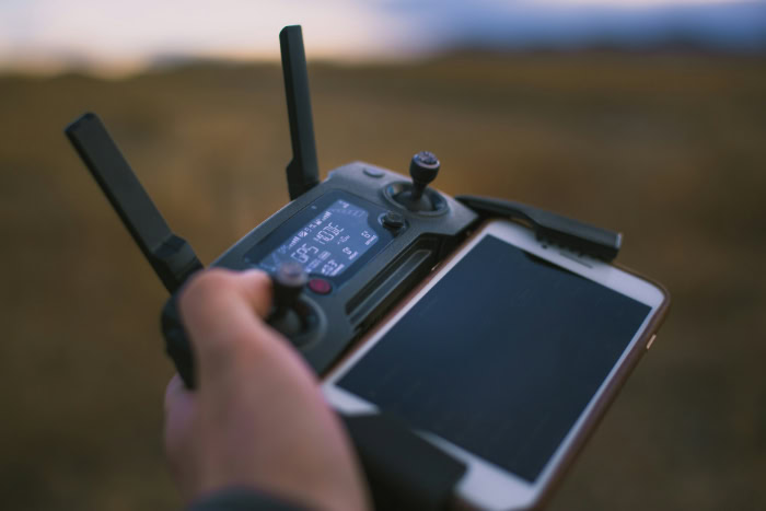 Hand holding drone remote controller with smartphone display