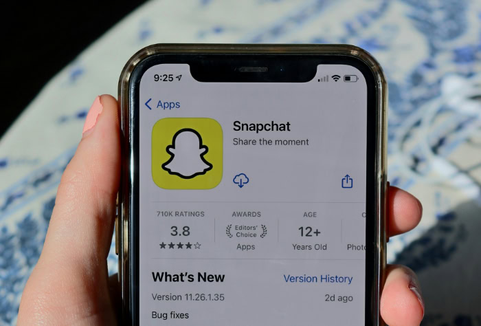 Hand holding iPhone displaying the Snapchat app