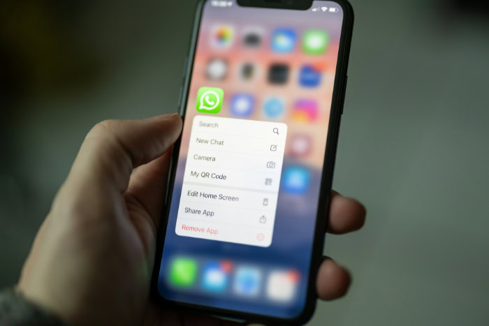 Hand holding iPhone with WhatsApp context menu open