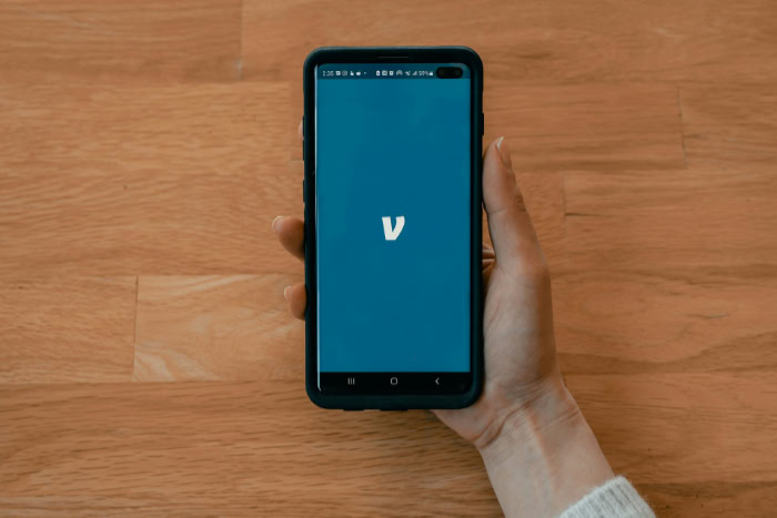 Hand holding phone displaying Venmo app logo